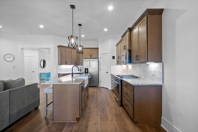 kitchen with light stone countertops, open floor plan, appliances with stainless steel finishes, and a sink