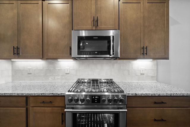 kitchen featuring decorative backsplash, appliances with stainless steel finishes, and light stone countertops