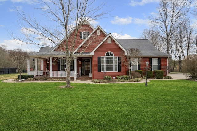 view of front facade with roof with shingles, a porch, and a front yard