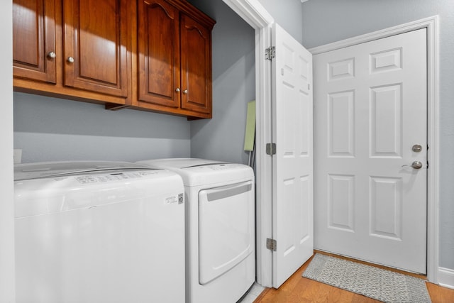 laundry room featuring washer and dryer, cabinet space, and light wood-type flooring