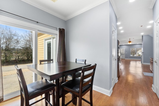 dining area featuring light wood-style flooring, baseboards, and ornamental molding