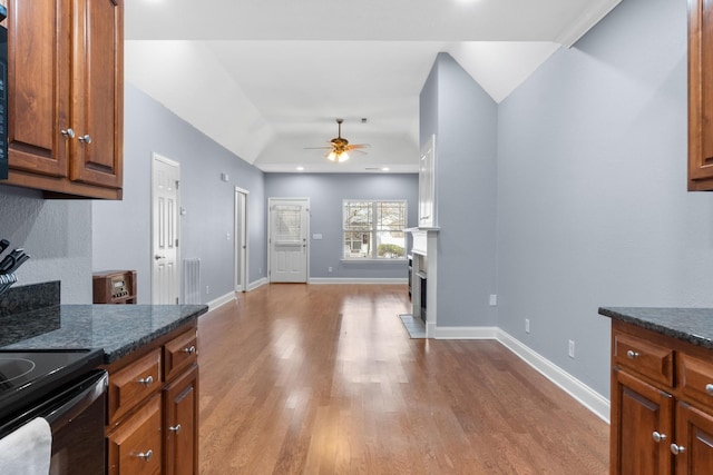 kitchen featuring a ceiling fan, wood finished floors, a fireplace, and baseboards