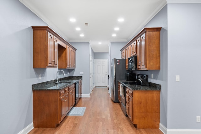 kitchen featuring light wood-type flooring, black appliances, dark stone counters, crown molding, and baseboards