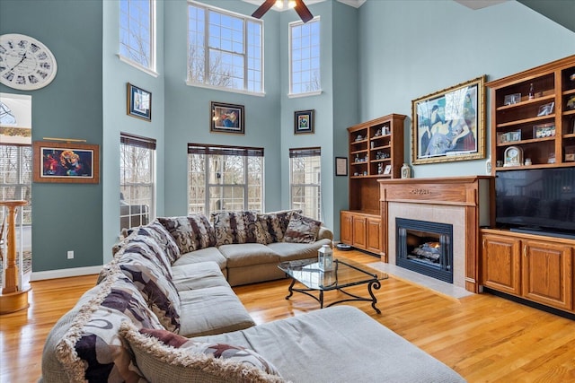 living area featuring plenty of natural light, light wood-style floors, baseboards, and a tile fireplace