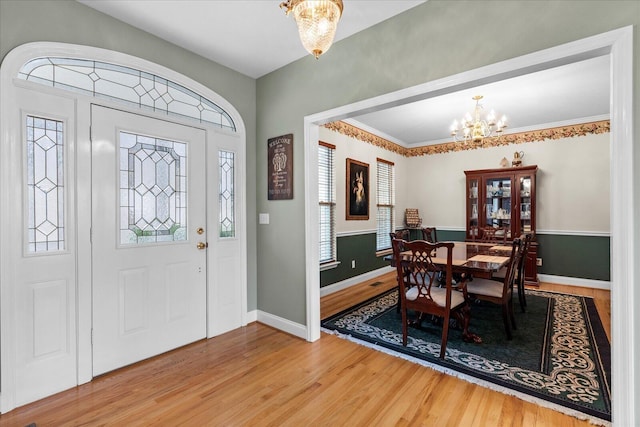 foyer entrance featuring a notable chandelier, baseboards, and wood finished floors