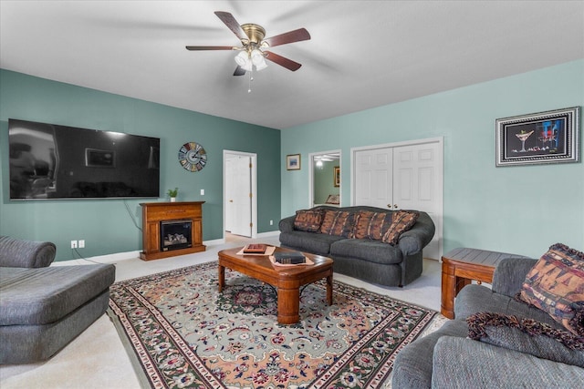 carpeted living area with a fireplace, baseboards, and a ceiling fan