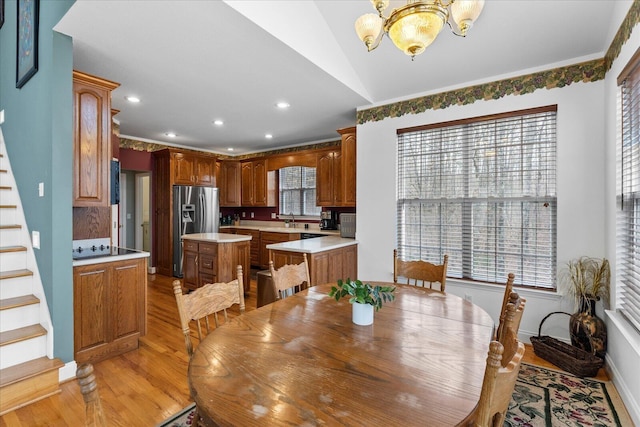 dining area featuring stairway, plenty of natural light, an inviting chandelier, and light wood finished floors