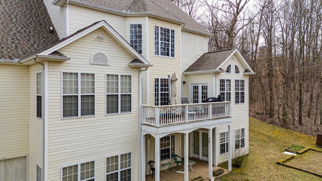 rear view of house featuring a yard, a shingled roof, and a patio