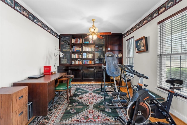 office space with crown molding, wood finished floors, baseboards, and ceiling fan