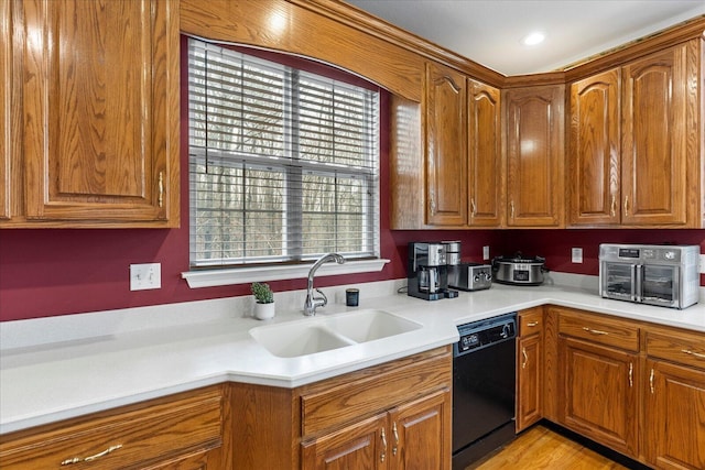 kitchen featuring light wood finished floors, light countertops, black dishwasher, brown cabinetry, and a sink