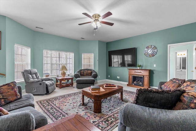 living room with carpet, visible vents, baseboards, a ceiling fan, and a glass covered fireplace