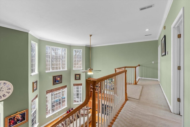 hallway featuring visible vents, baseboards, carpet, ornamental molding, and an upstairs landing