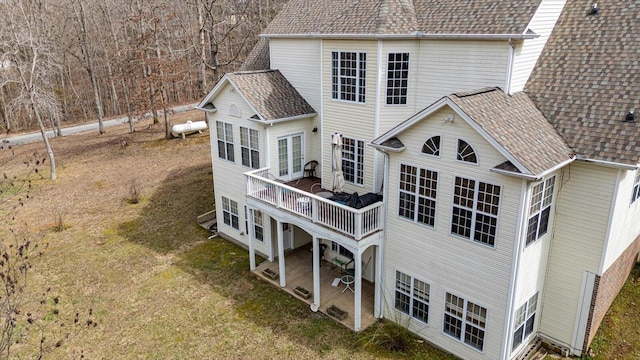 rear view of house featuring a shingled roof and a deck