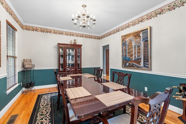 dining area with a chandelier, visible vents, baseboards, and wood finished floors