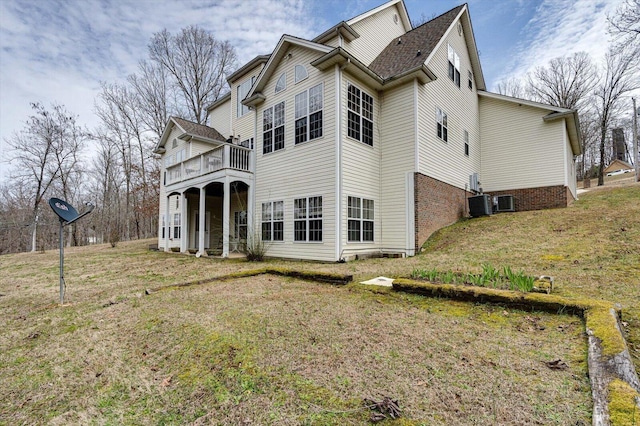 back of property featuring brick siding, a lawn, and central AC