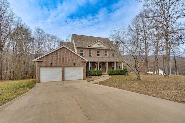 view of front of property featuring a front lawn, driveway, covered porch, a garage, and brick siding