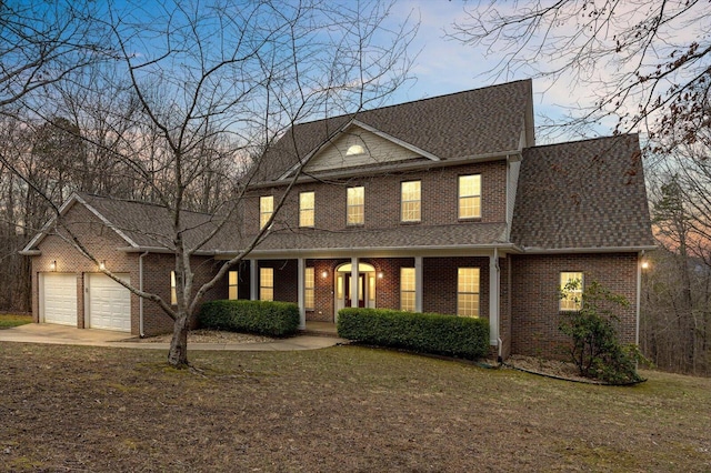 view of front of home with driveway, a front lawn, roof with shingles, an attached garage, and brick siding