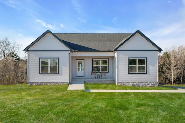 view of front of house featuring covered porch, a front lawn, and roof with shingles