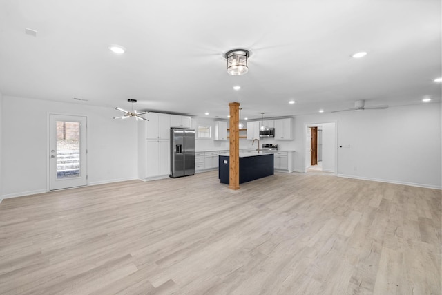 unfurnished living room featuring light wood-type flooring, a sink, recessed lighting, baseboards, and ceiling fan