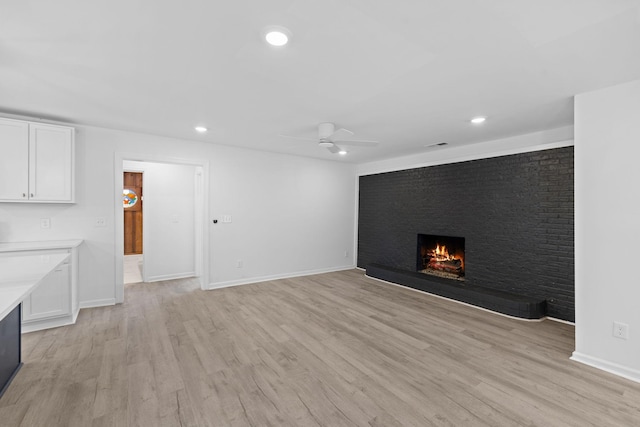 unfurnished living room with a ceiling fan, a brick fireplace, recessed lighting, and light wood-style flooring