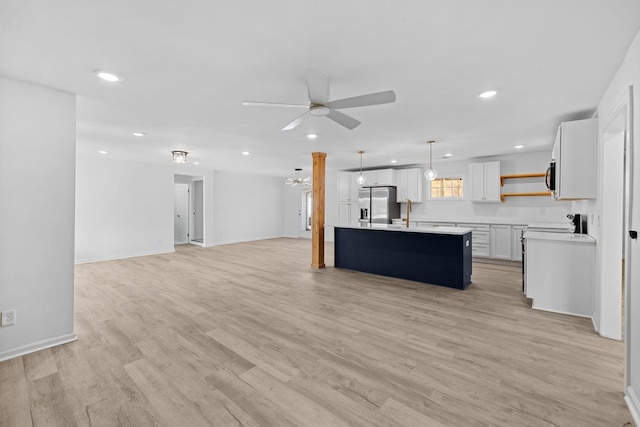 kitchen featuring open floor plan, light countertops, stainless steel fridge, a ceiling fan, and open shelves