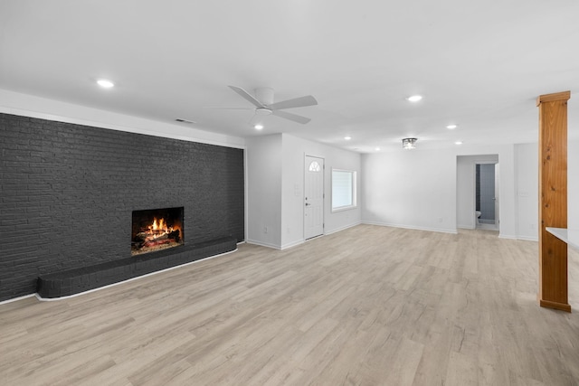 unfurnished living room with a brick fireplace, light wood-style flooring, recessed lighting, and baseboards