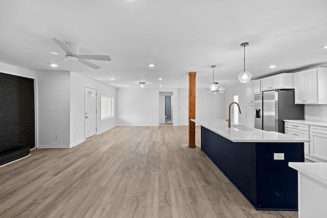 kitchen with a ceiling fan, stainless steel fridge with ice dispenser, light countertops, light wood-style floors, and open floor plan