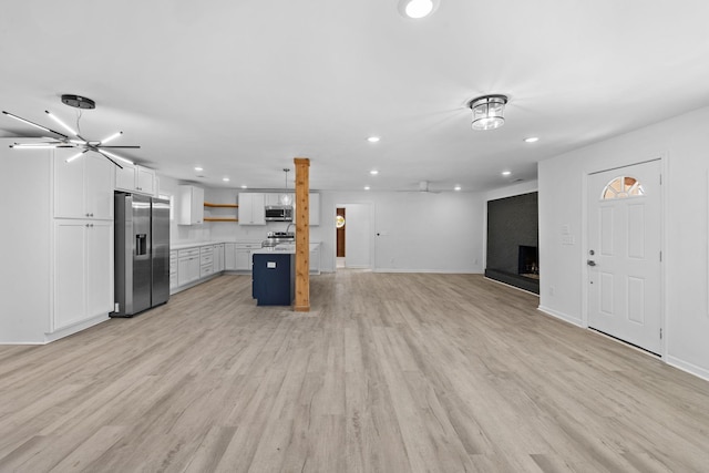 kitchen with open shelves, recessed lighting, stainless steel appliances, light countertops, and open floor plan