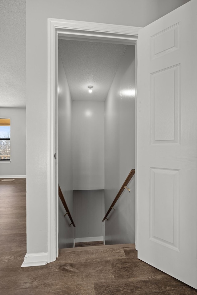 stairway featuring a textured ceiling and wood finished floors