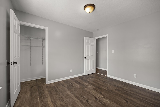 unfurnished bedroom with a closet, baseboards, a textured ceiling, and dark wood finished floors