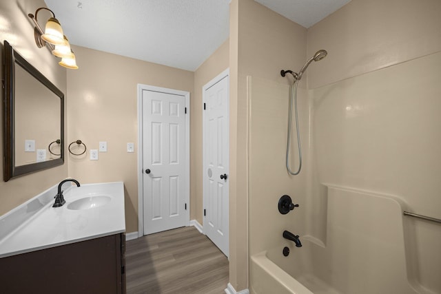 bathroom featuring baseboards, vanity, wood finished floors, a textured ceiling, and  shower combination