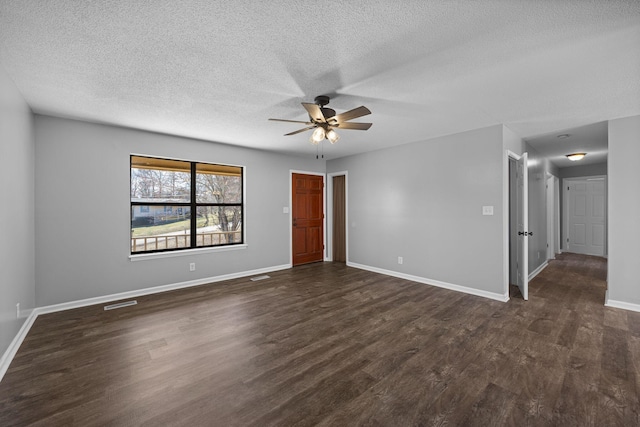 empty room with a ceiling fan, visible vents, baseboards, dark wood-type flooring, and a textured ceiling