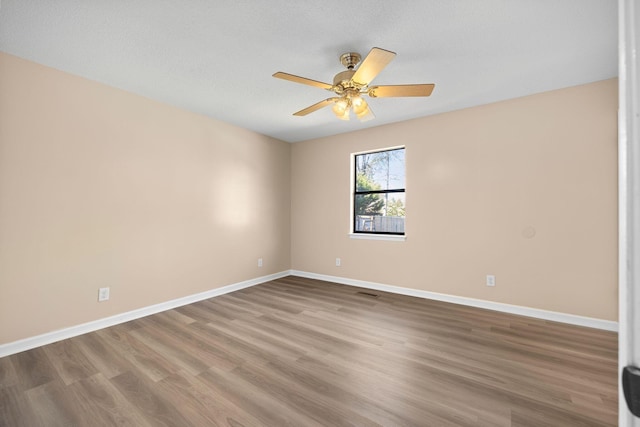 empty room with ceiling fan, baseboards, and wood finished floors