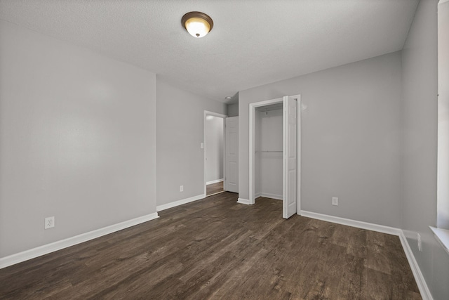 unfurnished bedroom featuring wood finished floors, baseboards, a closet, and a textured ceiling