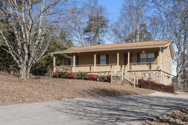 single story home with a porch, stone siding, and driveway