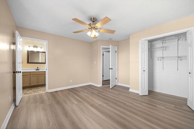 unfurnished bedroom with a closet, light wood-style flooring, baseboards, and a sink