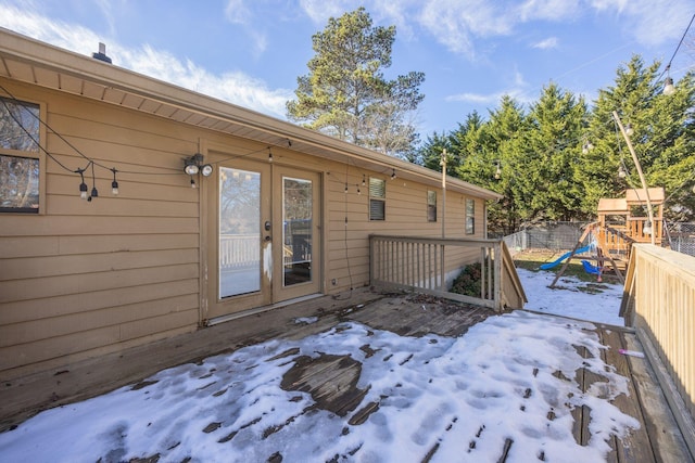 wooden deck with french doors, a playground, and fence