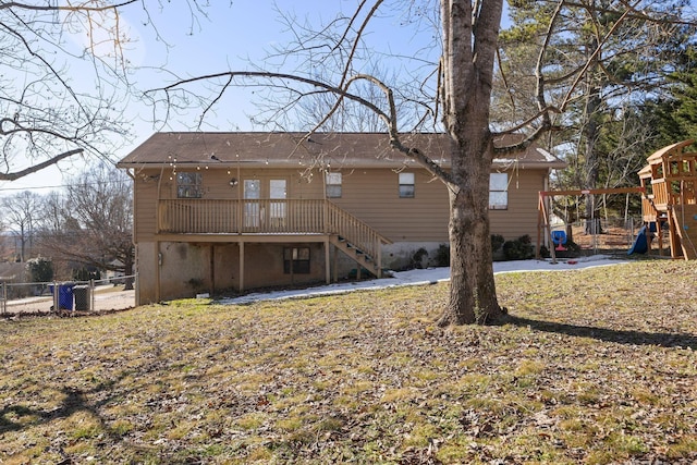 rear view of house with stairway, a playground, and fence