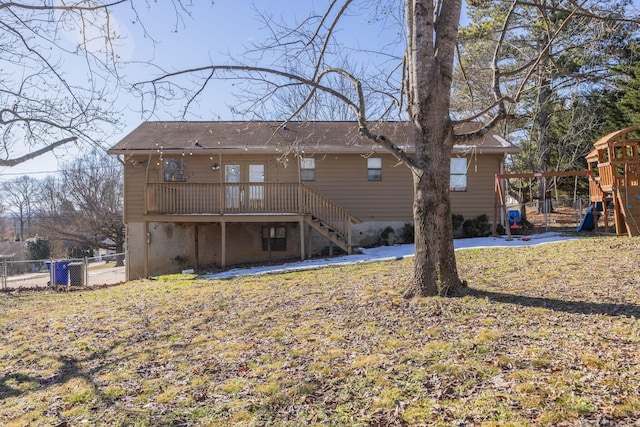 rear view of property with stairs, a playground, and fence