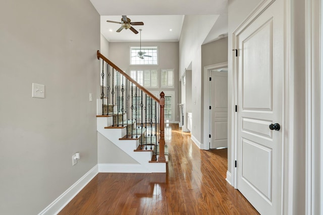 entryway with baseboards, a high ceiling, wood finished floors, and stairs