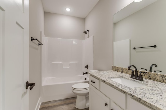 bathroom with vanity, toilet, wood finished floors, and shower / bathtub combination