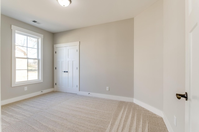 spare room with visible vents, baseboards, and light carpet