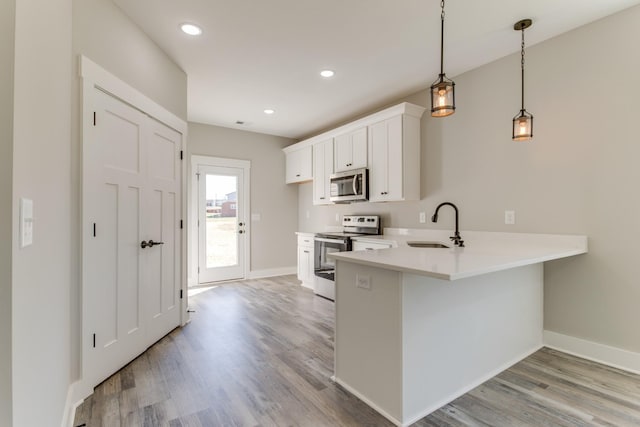 kitchen with light wood-style flooring, a sink, stainless steel appliances, light countertops, and white cabinetry