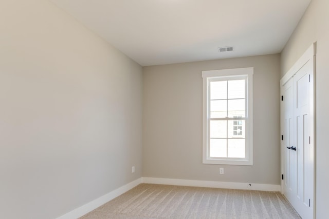 spare room featuring baseboards, visible vents, and light carpet