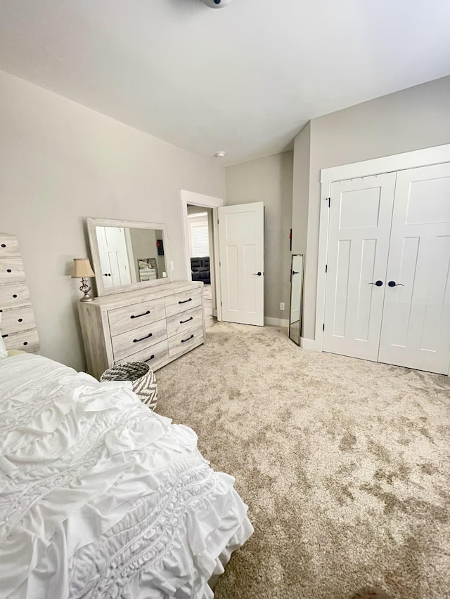 carpeted bedroom with a closet and baseboards