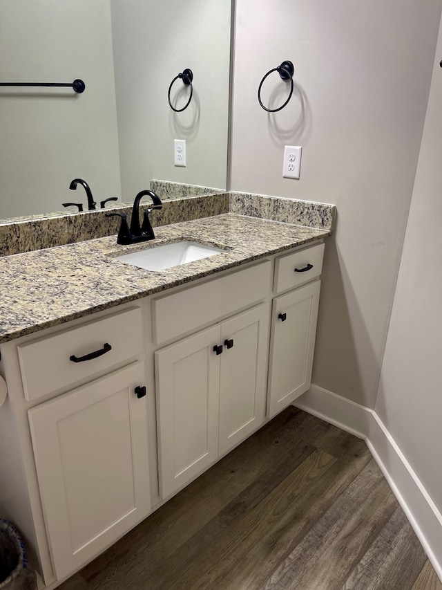 bathroom with vanity, wood finished floors, and baseboards