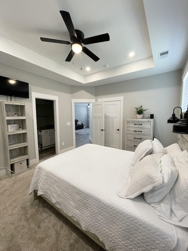 bedroom with visible vents, ensuite bathroom, recessed lighting, carpet floors, and a raised ceiling