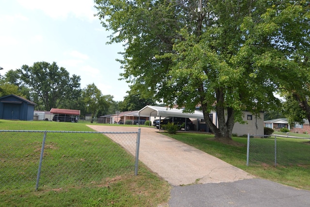 view of front of property featuring a front lawn, fence, driveway, and a carport