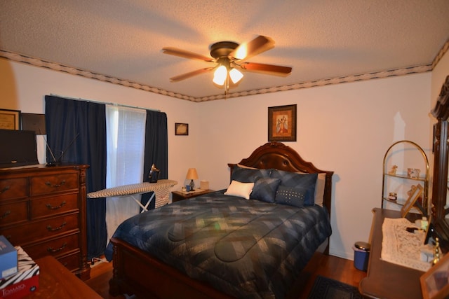 bedroom with ceiling fan, wood finished floors, and a textured ceiling