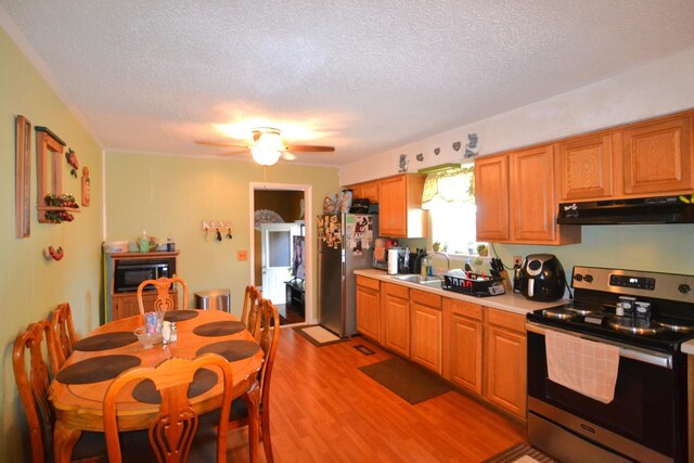 kitchen featuring light wood-style flooring, stainless steel appliances, light countertops, under cabinet range hood, and a textured ceiling